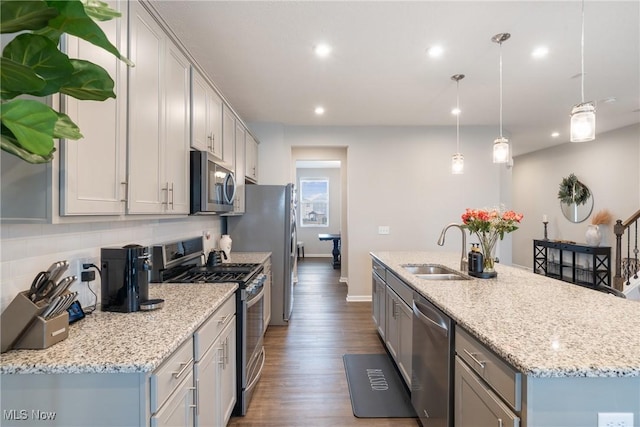 kitchen featuring dark wood finished floors, an island with sink, decorative backsplash, appliances with stainless steel finishes, and a sink