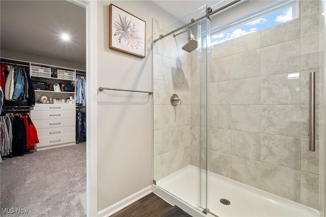 full bath with a walk in closet, baseboards, and a stall shower