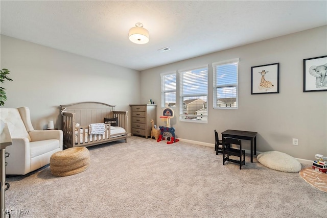 carpeted bedroom featuring visible vents, a crib, and baseboards