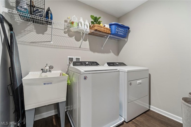 clothes washing area featuring dark wood-style floors, baseboards, laundry area, a sink, and independent washer and dryer