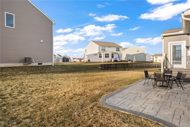 view of yard featuring a patio, central air condition unit, fence, and a residential view