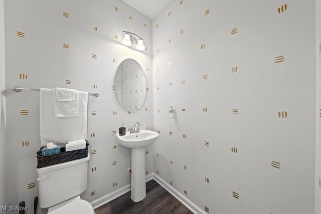 bathroom featuring toilet, wood finished floors, baseboards, and a sink