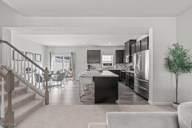 kitchen with a kitchen island, baseboards, light countertops, decorative backsplash, and appliances with stainless steel finishes