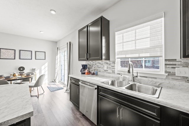 kitchen with a sink, backsplash, light countertops, and stainless steel dishwasher