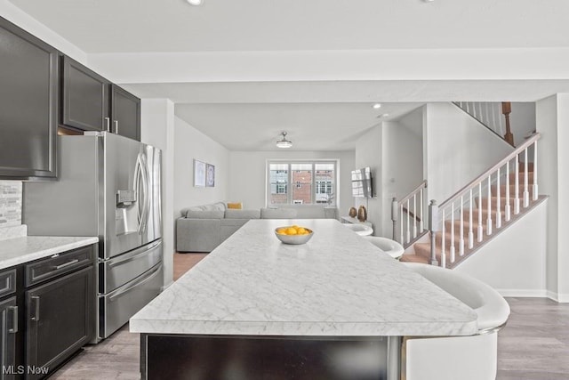 kitchen with a kitchen island, open floor plan, light countertops, light wood-style flooring, and stainless steel fridge