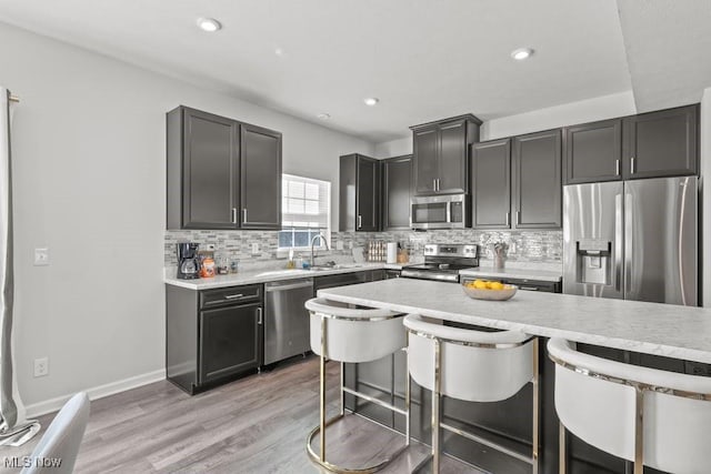 kitchen featuring a sink, stainless steel appliances, a kitchen bar, and backsplash