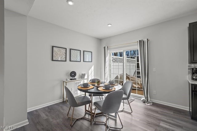 dining area with baseboards and dark wood-type flooring