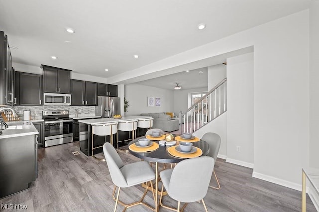 dining area with recessed lighting, baseboards, wood finished floors, and stairs