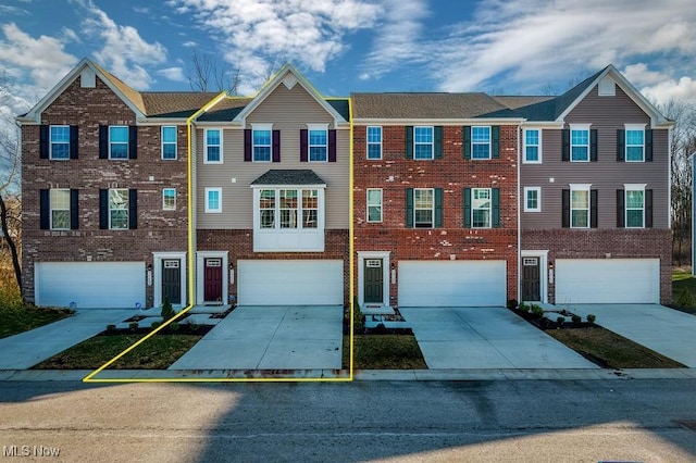 multi unit property featuring brick siding, a garage, and driveway