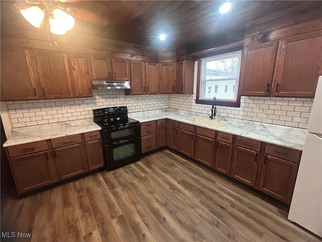 kitchen featuring a sink, double oven range, under cabinet range hood, dark wood-style floors, and decorative backsplash