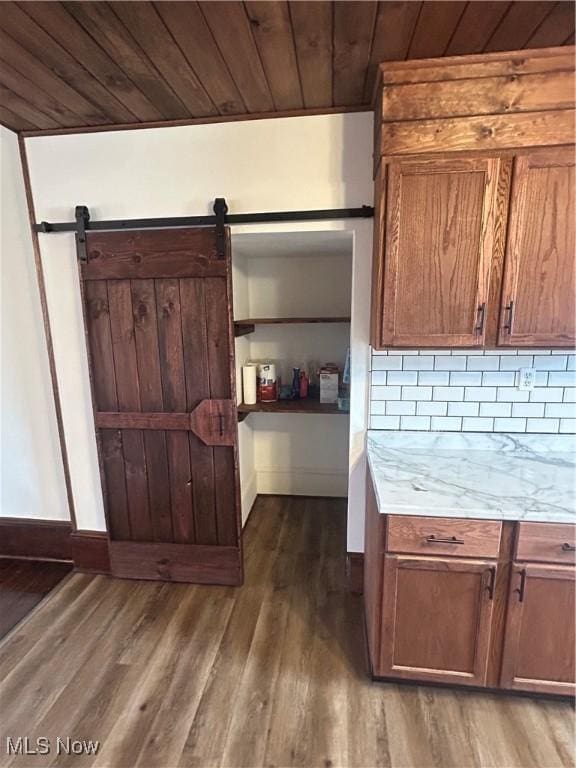 kitchen featuring wood finished floors, brown cabinets, light countertops, wood ceiling, and tasteful backsplash