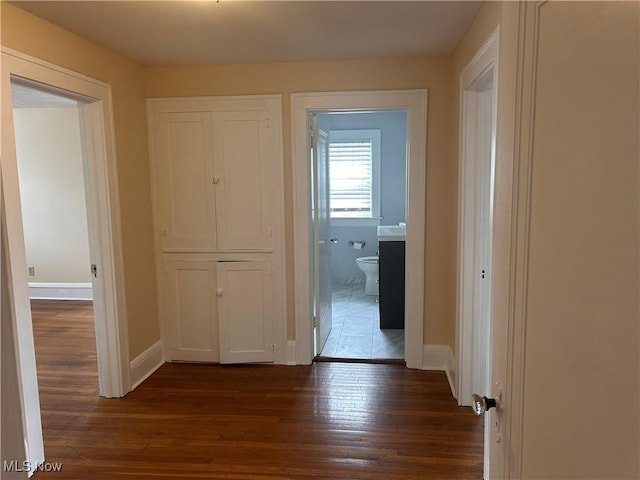 hallway featuring dark wood finished floors and baseboards