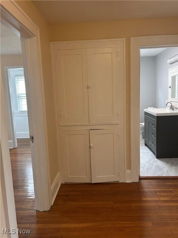 hall with a sink, baseboards, and wood finished floors