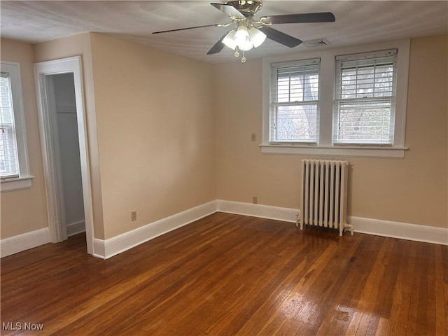 unfurnished room featuring radiator heating unit, a healthy amount of sunlight, baseboards, and wood-type flooring