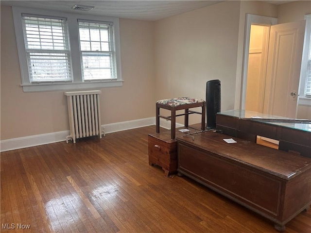 home office featuring visible vents, radiator, baseboards, and hardwood / wood-style floors