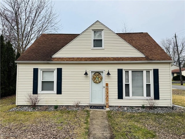 view of front facade featuring a front yard and a shingled roof