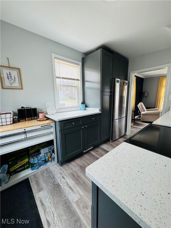 kitchen featuring light stone countertops, light wood-style floors, and freestanding refrigerator