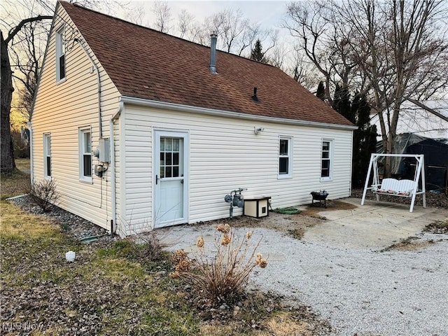 back of house with a patio and roof with shingles