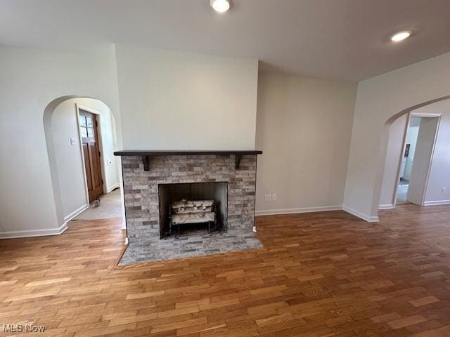 1119 Abbey Pl, Zanesville, OH 43701 - unfurnished living room with arched walkways, a fireplace, baseboards, and wood finished floors