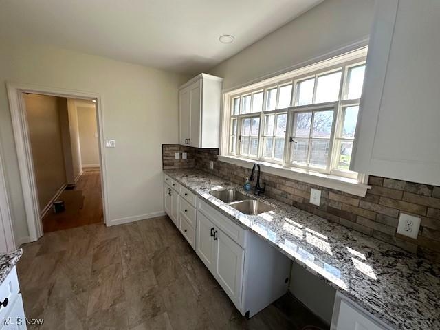 1119 Abbey Pl, Zanesville, OH 43701 - kitchen with a sink, backsplash, white cabinets, baseboards, and light stone countertops