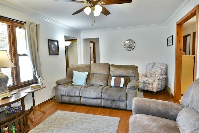 living room featuring baseboards, wood finished floors, a ceiling fan, and crown molding