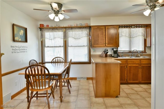 kitchen featuring a sink, light countertops, brown cabinets, and ceiling fan