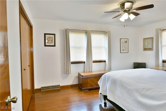 bedroom with multiple windows, wood finished floors, visible vents, and a closet