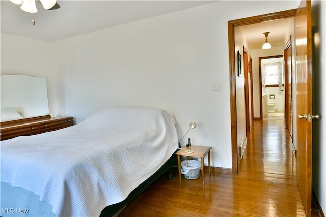 bedroom featuring baseboards, wood finished floors, and a ceiling fan