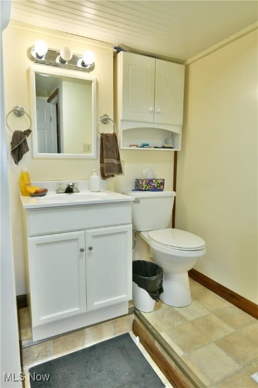 half bath featuring vanity, toilet, and baseboards