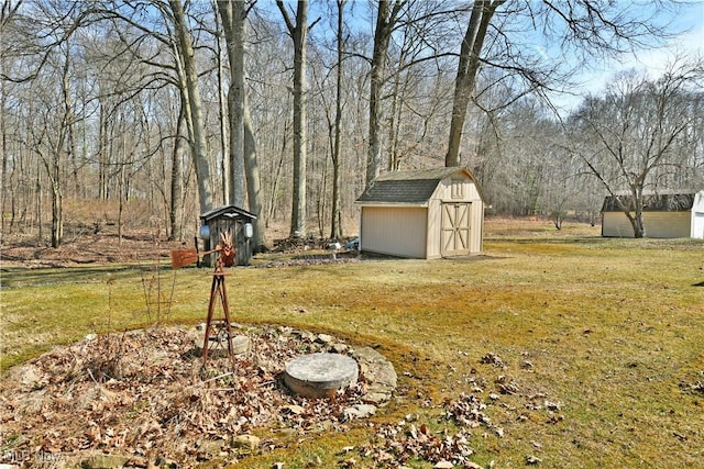 view of yard with a shed, a forest view, and an outdoor structure