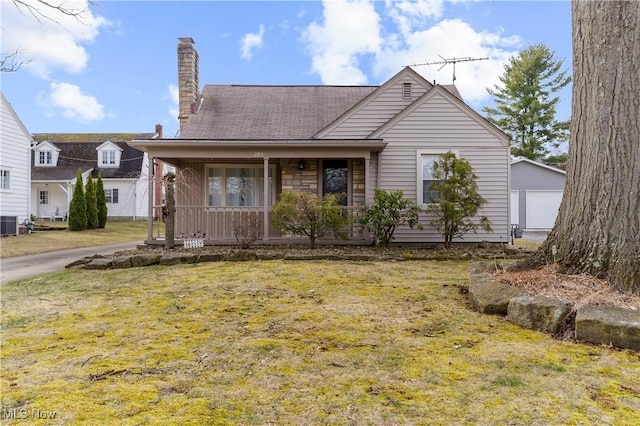 view of front of property with a porch, cooling unit, an outdoor structure, a front yard, and a chimney