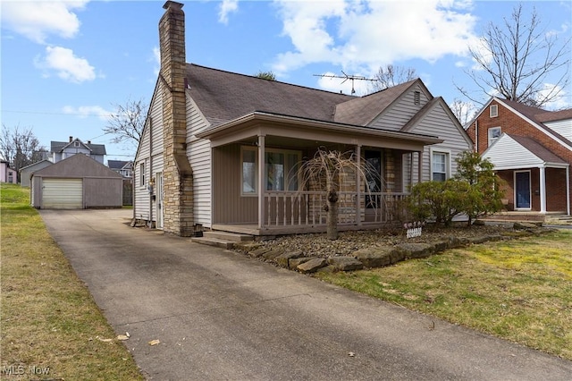 view of front of home featuring aphalt driveway, covered porch, an outdoor structure, a garage, and a chimney