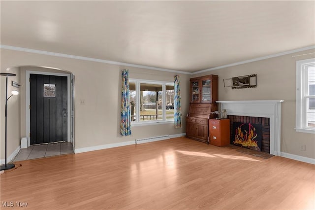 unfurnished living room featuring light wood finished floors, arched walkways, ornamental molding, a brick fireplace, and baseboard heating