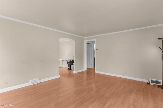 empty room featuring arched walkways, visible vents, light wood-style flooring, and baseboards