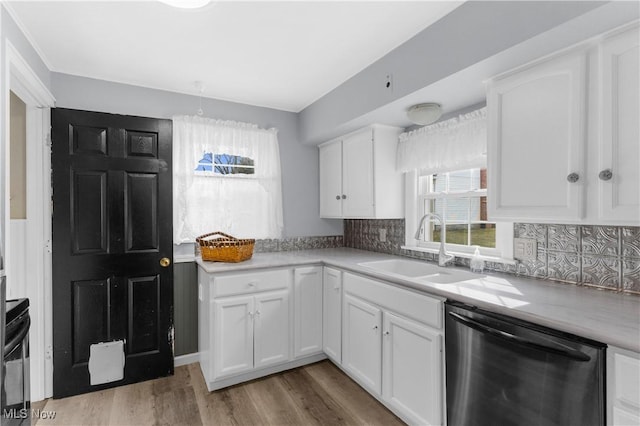 kitchen with a sink, white cabinetry, light countertops, decorative backsplash, and dishwasher