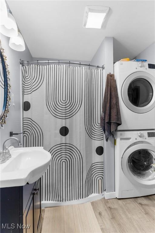 washroom with laundry area, light wood-style flooring, and stacked washing maching and dryer