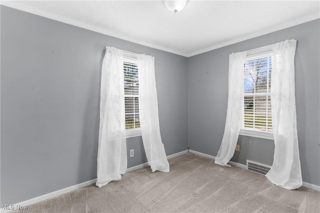 carpeted empty room with visible vents, baseboards, and ornamental molding