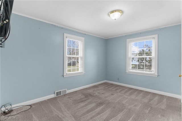 spare room featuring a wealth of natural light, carpet flooring, baseboards, and visible vents