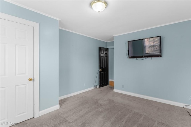 carpeted empty room featuring baseboards and ornamental molding