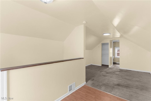 additional living space with visible vents, baseboards, carpet flooring, and vaulted ceiling