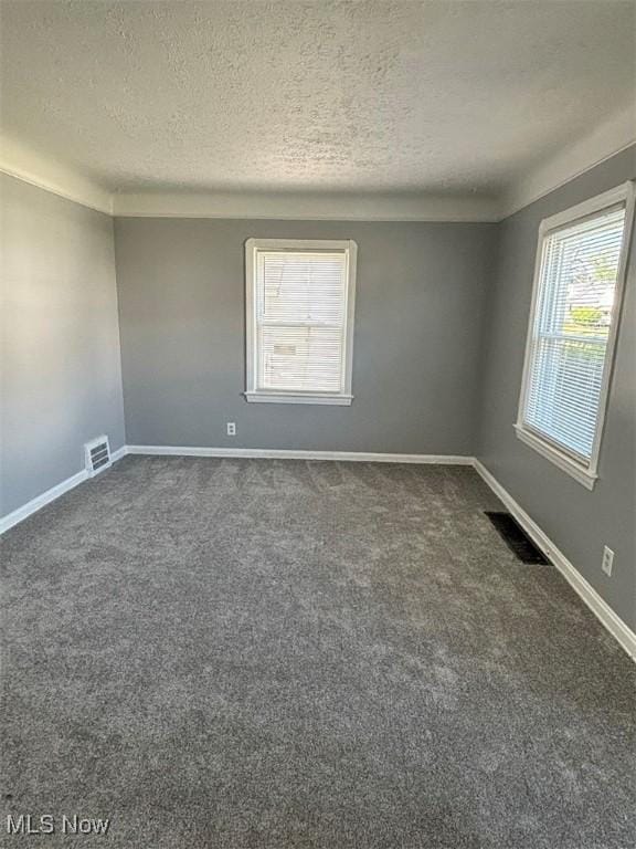 unfurnished room featuring visible vents, baseboards, and dark carpet