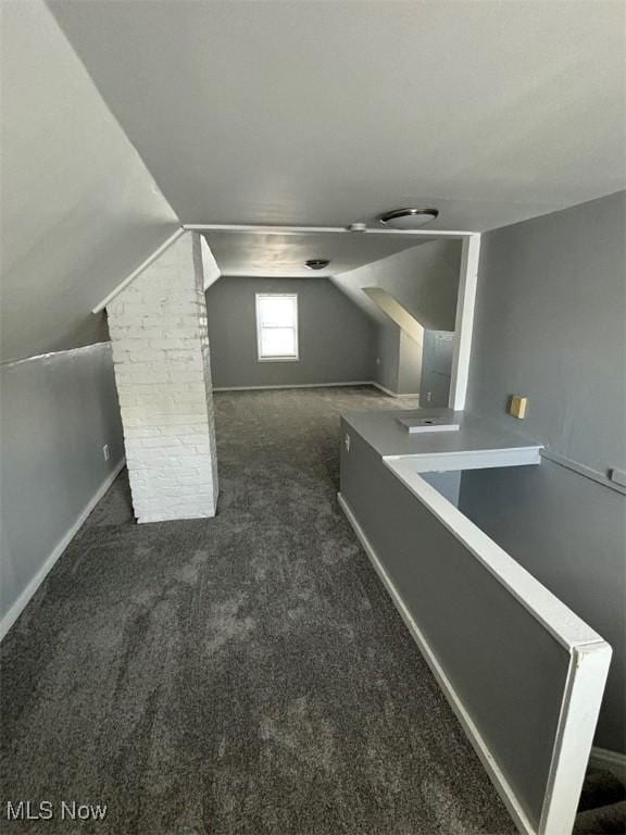 additional living space featuring dark colored carpet and vaulted ceiling