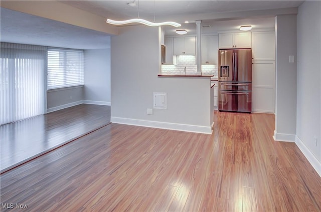 12900 Lake Ave Unit 820, Lakewood, OH 44107 - kitchen with backsplash, baseboards, light wood-style flooring, white cabinets, and stainless steel fridge