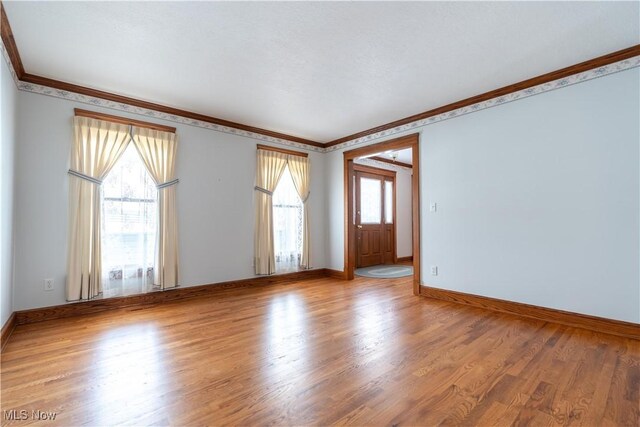 spare room with ornamental molding, wood finished floors, and a healthy amount of sunlight