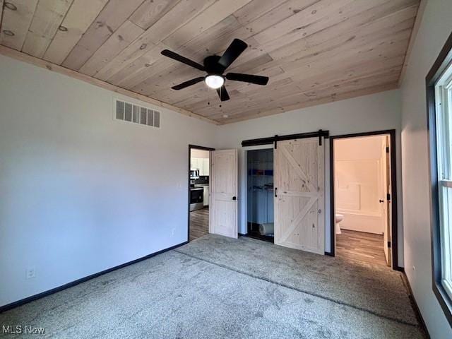 unfurnished bedroom with visible vents, baseboards, wood ceiling, a barn door, and carpet flooring