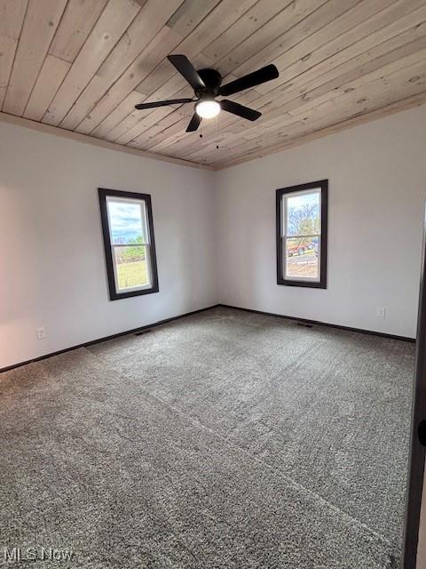 empty room featuring ceiling fan, baseboards, wooden ceiling, and carpet flooring