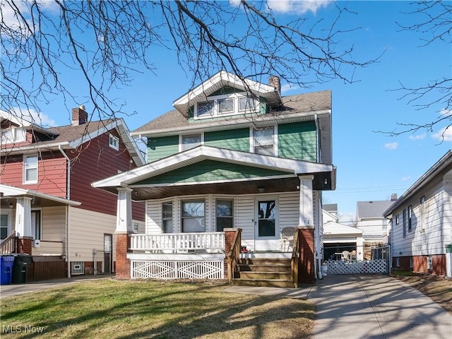 american foursquare style home with a front yard, covered porch, and a chimney