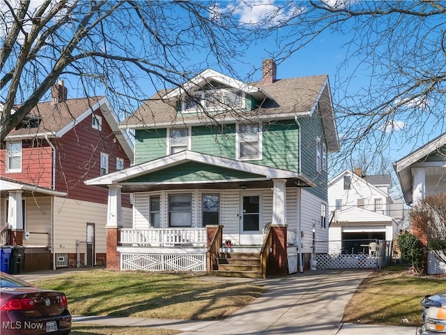 american foursquare style home with driveway, a porch, a shingled roof, a chimney, and a front lawn