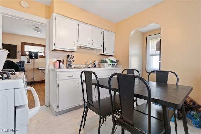 kitchen with light countertops, white cabinets, plenty of natural light, and arched walkways