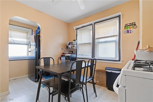 dining area featuring arched walkways, ceiling fan, and baseboards